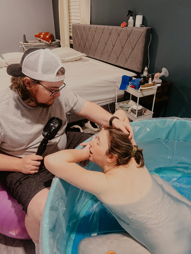 my husband keeping me cool with a handheld fan as I labor in the birth pool