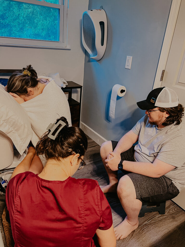 my midwife checking my sons hear rate as i labor on the toilet backwards